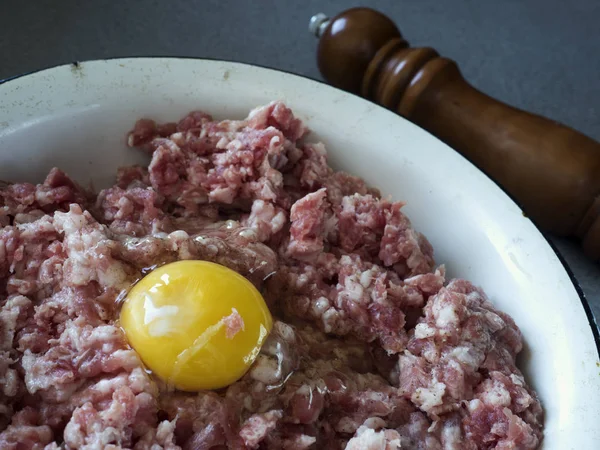 Gehakt vlees voor schnitzels met rauw ei in een kom glazuur. — Stockfoto