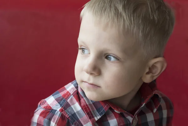 Niño caucásico en camisa a cuadros sobre fondo rojo —  Fotos de Stock