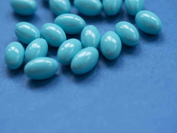 Niebieskie tabletki na ciemnoniebieskim tle — Zdjęcie stockowe