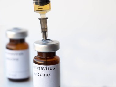 The world is anxiously awaiting a vaccine against coronavirus. The photo illustration shows two vials labeled Coronavirus vaccine and syringe. clipart