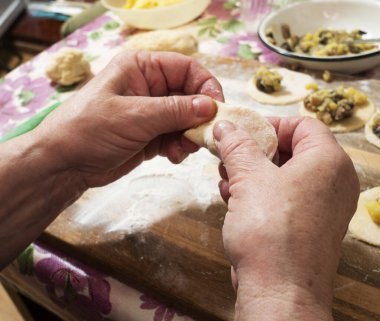 Yaşlı kadın patatesli ve mantarlı popüler bir hamur tatlısı hazırlıyor. Ukrayna Bakanlar Kurulu 'nun kararnamesi uyarınca COVID-19 salgını sırasında milyonlarca emekli yurtiçinde karantinaya alınmak zorunda kalıyor..