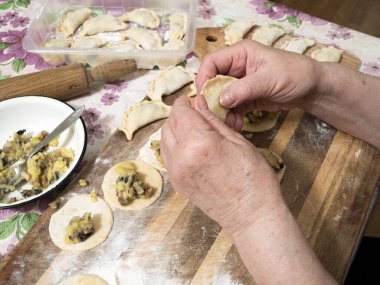 Yaşlı kadın patatesli ve mantarlı popüler bir hamur tatlısı hazırlıyor. Ukrayna Bakanlar Kurulu 'nun kararnamesi uyarınca COVID-19 salgını sırasında milyonlarca emekli yurtiçinde karantinaya alınmak zorunda kalıyor..