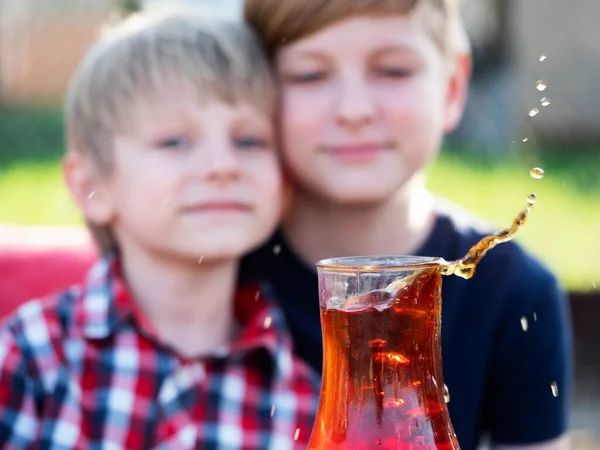 二人の白人の少年は 砂糖の落下部分からカップの中のお茶のスプラッシュを見て — ストック写真