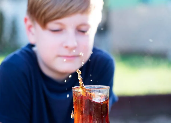 白人男孩从掉下来的糖中看到一杯茶中的水花 — 图库照片