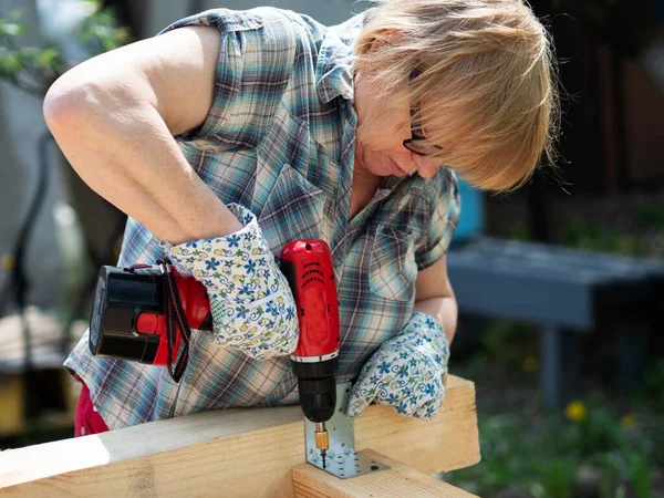 Senior Caucasian Woman Assembles Wooden Frame Building Using Metal Fasteners — Stock Photo, Image