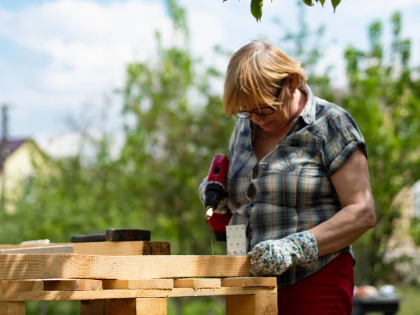Starsza Kaukaska Kobieta Montuje Drewnianą Ramę Budynku Pomocą Metalowych Elementów — Zdjęcie stockowe