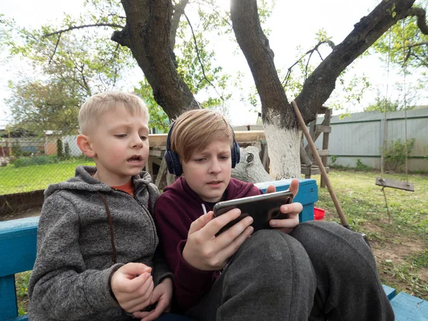 Två Kaukasiska Pojkar Bröder Spelar Smartphone Sitter Trädgården — Stockfoto
