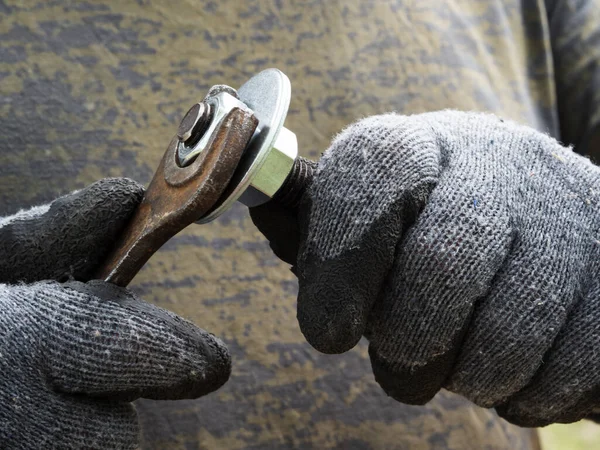 男性手戴手套用扳手拧紧螺母上的螺母 — 图库照片