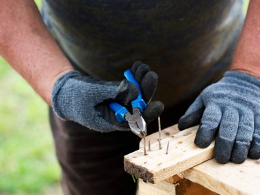 Parçalanmış paletlerden çiviler çıkarılıyor