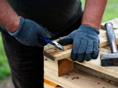 Parçalanmış paletlerden çiviler çıkarılıyor