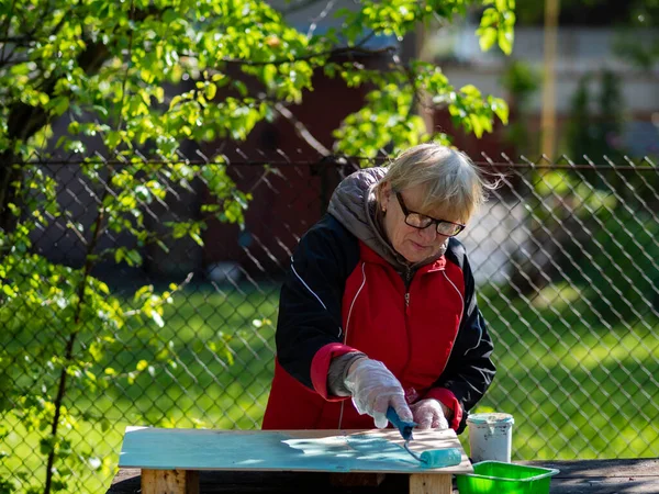 Senior Caucasian Woman Paints Turquoise Plywood Sheet Paint Roller — Stock Photo, Image