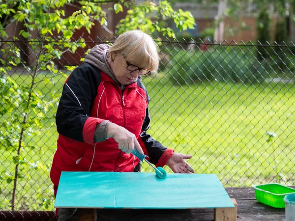 Senior Blanke Vrouw Schildert Turquoise Multiplex Vel Met Een Verfroller — Stockfoto