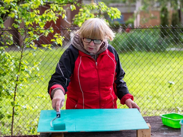 Senior Caucasian Woman Paints Turquoise Plywood Sheet Paint Roller — Stock Photo, Image