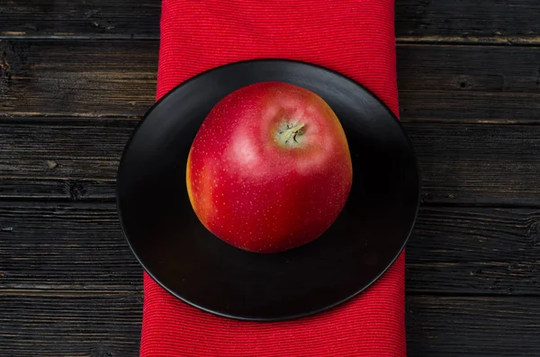 Czerwone jabłko w czarnej płycie — Zdjęcie stockowe
