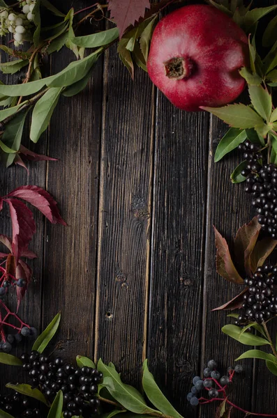 Granátové jablko a listy na černém pozadí dřevěná — Stock fotografie