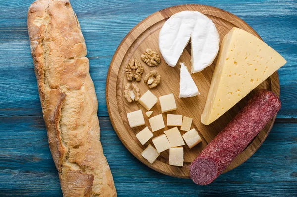 Assorted cheeses on round wooden board plate — Stock Photo, Image