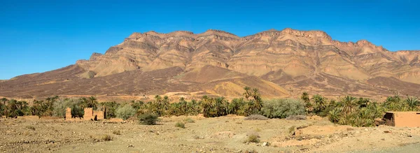 Casas de barro marroquíes cerca de montañas y palmeras —  Fotos de Stock