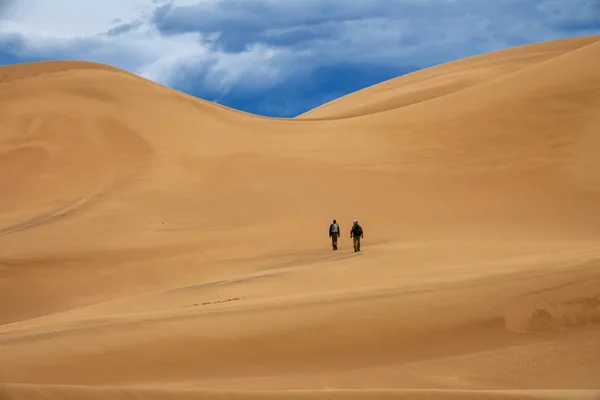 Travelers in desert dunes in mountains — Stock Photo, Image