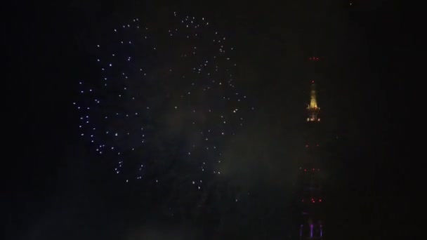 Espectáculo de fuegos artificiales y torre de televisión en el cielo nocturno — Vídeos de Stock