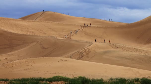 Turistas escalam altas dunas de areia no deserto — Vídeo de Stock