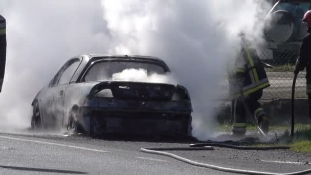 Feuerwehrleute Löschen Brennendes Auto Auf Der Straße — Stockvideo