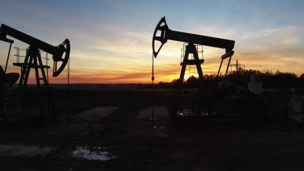 Bei Sonnenuntergang in der Nähe funktionierender Ölpumpen — Stockvideo
