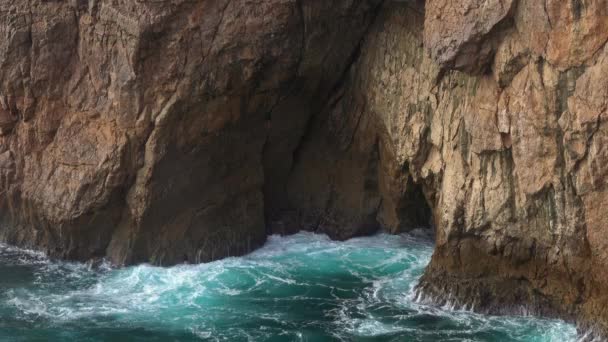 A tenger hullámai szikla formájában hatolnak be egy barlangba és fröcskölnek. — Stock videók