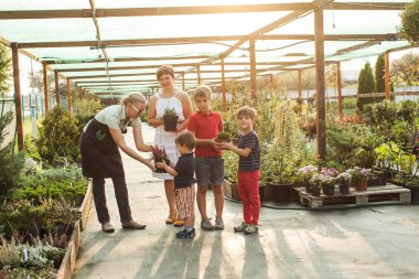 Kadın bahçıvan çocuklara çiçek verir.