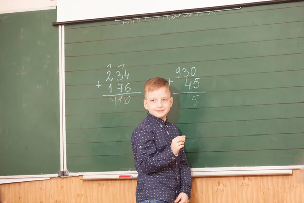 School jongen lost voorbeelden op het bord — Stockfoto