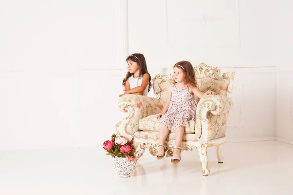 Zwei Mädchen sitzen in einem prachtvollen antiken Sessel — Stockfoto