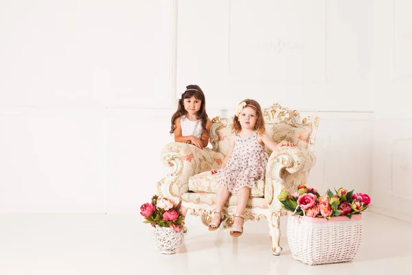 Dvě dívky sedí v nádherné staré křeslo — Stock fotografie