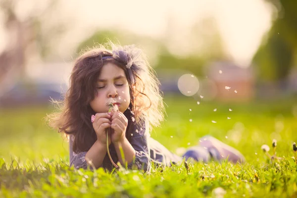 Cute girl blowing dandelion — Stock Photo, Image