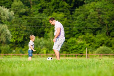 Baba oğul futbol oynuyor.