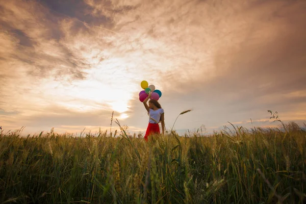 Girl with balloons in wheat field — Stock Photo, Image