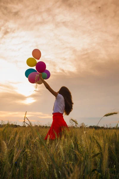 Дівчина з повітряними кулями в пшеничному полі — стокове фото