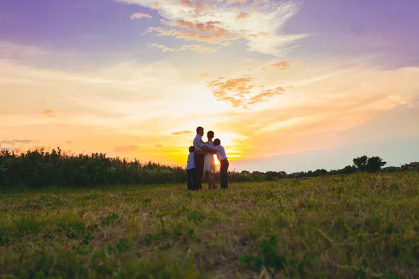 Happy family on the background of the sunset — Stock Photo, Image