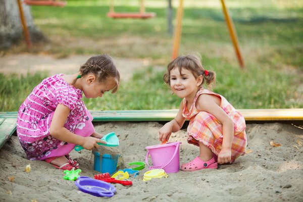 Two girls play in the sandbox