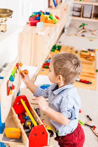 Menino brinca com brinquedos de madeira — Fotografia de Stock