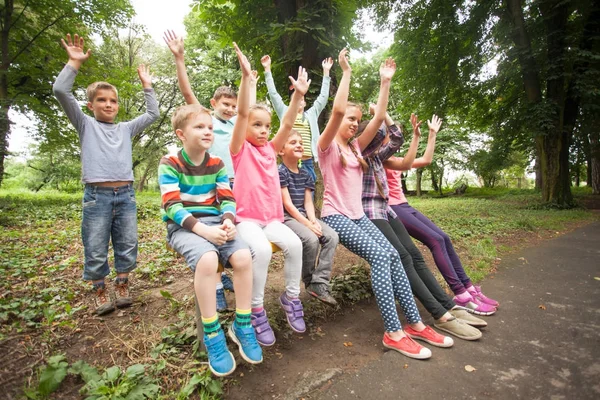 Grupo de crianças em um banco de parque — Fotografia de Stock