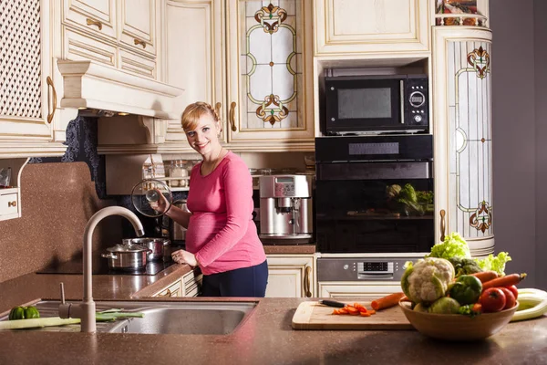 Mujer embarazada está cocinando —  Fotos de Stock