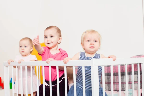 Three baby girls in the crib — Stock Photo, Image