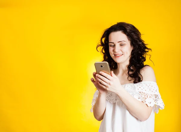 Kobieta, trzymając smartfon na żółtym tle — Zdjęcie stockowe
