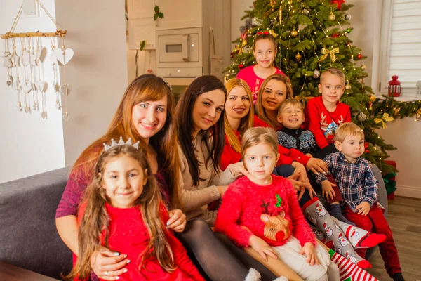 Ung kvinna med sina barn sitter tillsammans nära julgran — Stockfoto