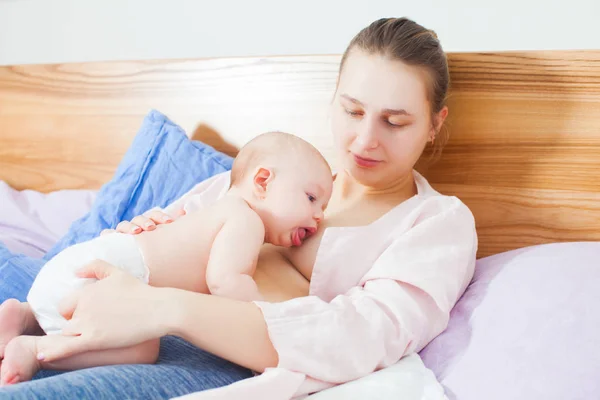 Young woman feeding baby in a bedroom. — Stock Photo, Image