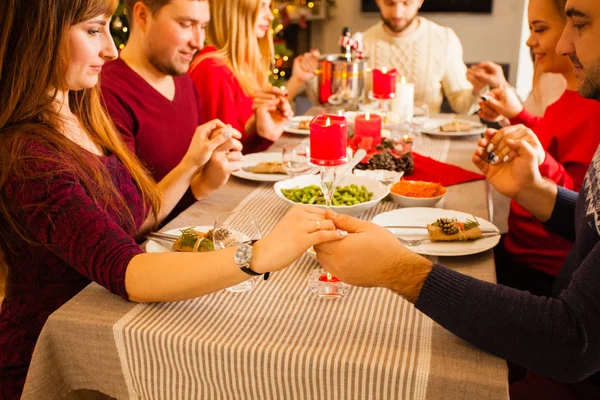 Fiatal család és barátok imádkoznak és áldják az asztalt a karácsonyi vacsoránál — Stock Fotó