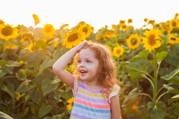 Glückliche Tochter im Sonnenblumenfeld an einem warmen Sommertag. — Stockfoto