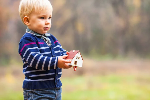 Cute baby boy holding model of the house outdoors — ストック写真