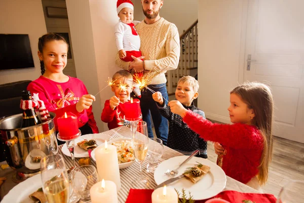 Happy kids with sparklers in hands at Christmas party at home. — Stockfoto