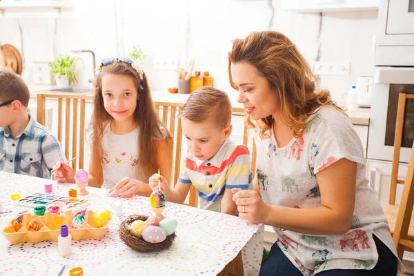 Mutter und Kinder bemalen und verzieren bunte Eier — Stockfoto