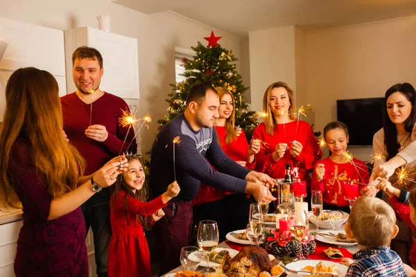 Happy family with sparklers having fun at dinner party at home — ストック写真